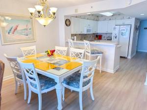 a dining room with a table and chairs and a kitchen at Ashworth 303 in North Myrtle Beach