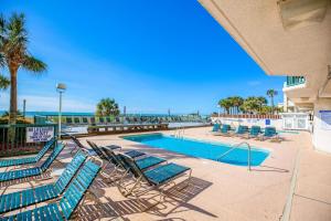 a swimming pool with lounge chairs and the ocean at Ashworth 903 in North Myrtle Beach