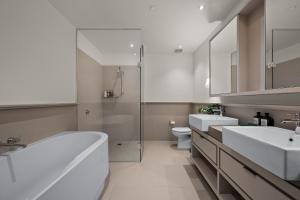 a bathroom with a tub and a sink and a toilet at Opulent Harbourside Sanctuary in Melbourne +28 photos