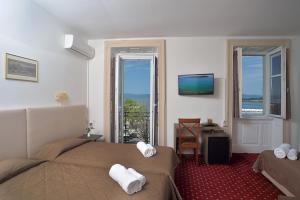 a bedroom with two beds and a desk and two windows at Konstantinoupolis in Corfu