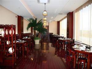 a restaurant with wooden tables and chairs and a palm tree at Dunhuang Grand Soluxe Hotel in Dunhuang