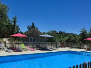 a swimming pool with chairs and umbrellas at Le Village Enchanteur in La Chapelle-Aubareil
