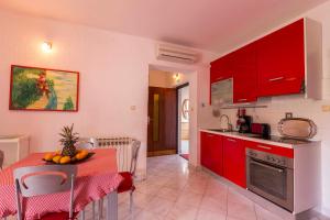 a kitchen with red cabinets and a table with fruit on it at Apartments Sunčica in Mali Lošinj