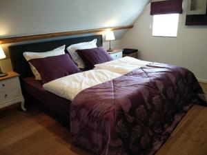 a bedroom with a large bed with purple sheets and pillows at de Twie Keuninge in Maasmechelen