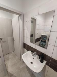 a white bathroom with a sink and a mirror at Krásny nový prízemný apartmán in Nové Zámky