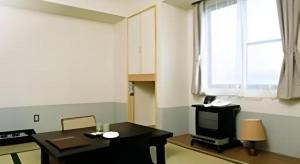 a room with a table and a television and a window at Hirosaki Ekimae Hotel in Hirosaki