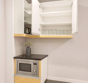 a kitchen with white cabinets and a microwave on a counter at Villa Vi Casa in Ban Rong Po