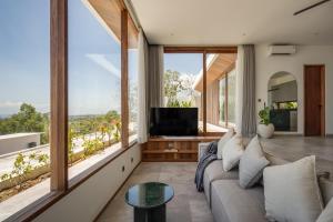 Una sala de estar con un sofá y grandes ventanales. en Brand new 2-bedroom ocean view villa, en Uluwatu