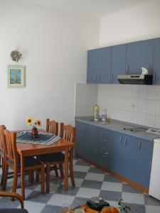 cocina con armarios azules, mesa y sillas en Apartments Capitano Blue, en Zaton