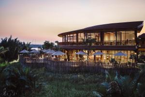 a building with tables and umbrellas in front of it at Namia River Retreat - Wellness Inclusive Resort in Hoi An