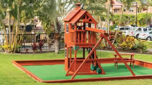 a playground with a play structure on the grass at Kona Coast Resort in Kailua-Kona