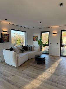 a white living room with a couch and a table at Exclusive apartment with a hot tub and view in Niederdorla