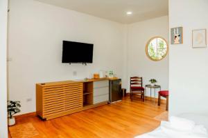 a living room with a television on a white wall at Patcharapon Resort in Ban Pong