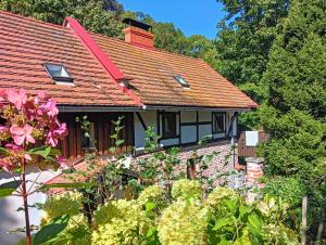 a house with a red roof and some flowers at Dom Przytulisko in Janowiec