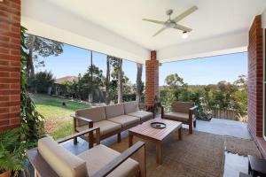 a patio with a couch and chairs and a ceiling fan at Gold Coast Family Stay - 4BR Near Theme Parks in Gold Coast