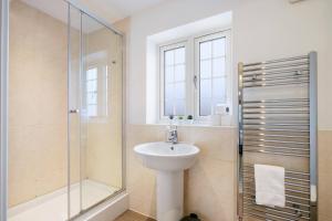 a white bathroom with a sink and a shower at 6 Bedroom 3 Bathroom House in Bicester Village in Bicester +46 photos