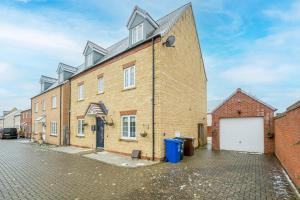 a large brick building with a white garage at 6 Bedroom 3 Bathroom House in Bicester Village in Bicester