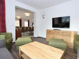 Una sala de estar con televisión, mesa y sillas. en Modern chalet with sauna near ski area in Saalbach-Hinterglemm Salzburgerland, en Saalbach Hinterglemm