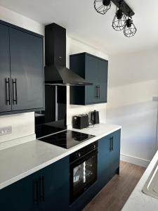 a kitchen with blue cabinets and a stove top oven at Seaside Home - Spacious Rooms - TV's in Every Room in Cleethorpes +15 photos