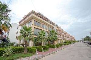a building with palm trees in front of a street at Nandan Retreat 4-Star Hotel & Luxury Villas Near Prem Mandir, Vrindavan in Vrindāvan