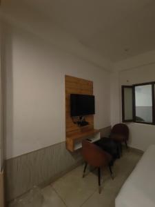 a bedroom with a desk with a television and two chairs at Jolly Luxury Resort in Gangtok