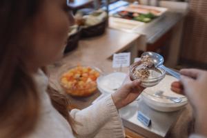 a woman is eating food with a spoon at Hotelli Helmi in Turku