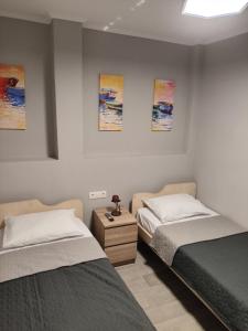 two beds in a room with paintings on the wall at Neapolis Apartment in Kavála