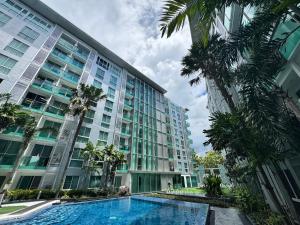 a large building with a swimming pool and palm trees at City Center Residence & Hot Hot Hot in Pattaya Central