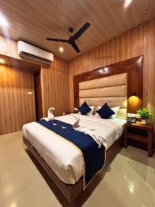 a bedroom with a large bed with a ceiling fan at Hotel Ashraya International in Mumbai