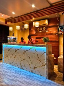 two men standing behind a counter in a kitchen at Hotel Ashraya International in Mumbai