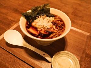 een kom soep op een houten tafel met een lepel bij Kominka Sauna & BBQ TK-tei in Ichihara