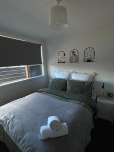ein Schlafzimmer mit einem Bett mit einem weißen Handtuch darauf in der Unterkunft Relax at Jollie-Cozy 3-Bedroom Home, Central Twizel in Twizel