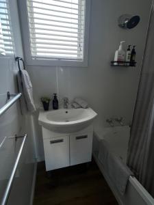 a white bathroom with a sink and a bath tub at Relax at Jollie-Cozy 3-Bedroom Home, Central Twizel in Twizel +10 photos