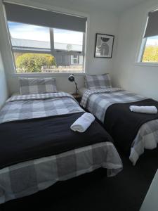 zwei Betten in einem Zimmer mit Fenster in der Unterkunft Relax at Jollie-Cozy 3-Bedroom Home, Central Twizel in Twizel + 12 Fotos