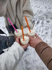 a person holding three drinks in their hands in the snow at Wellness Vila Limaco Slovakia in Horné Jaseno