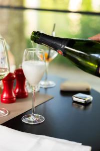 une bouteille de vin versée dans un verre à vin dans l'établissement El Toro am Seilersee Suiten und Restaurant, à Iserlohn