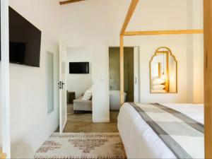 une chambre blanche avec un lit et un miroir dans l'établissement Nooitgedacht Guest Farm Cottages, à Kayamnandi