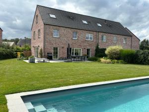 a brick house with a swimming pool in front of it at Brabant house with pool in Rixensart