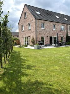 a large brick building with a green lawn in front of it at Brabant house with pool in Rixensart