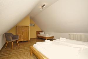 a attic bedroom with two beds and a chair at Balkon mit Meerblick, gratis Nutzung vom AHOI Erlebnisbad und Sauna in Sellin - Haus De niege Wech FeWo 03 in Thiessow +26 photos