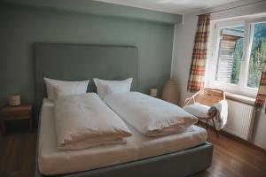 Una cama con sábanas blancas y almohadas en un dormitorio. en Am Sonnenhang, en Hirschegg