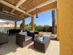 an outdoor patio with wicker chairs and a table at Casa Vida La Vida in Mazarrón