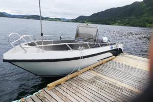 a white boat parked at a dock on a lake at Great House with a panoramic view in Storsæter