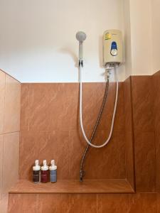 a shower in a bathroom with three bottles on a shelf at ClayHouse SAMUI Boutique Hotel in Koh Samui