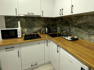 a kitchen with white cabinets and a sink and a microwave at Comfort House Партизанська 25 in Bila Tserkva