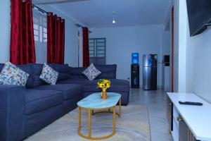 a living room with a blue couch and a table at LADIVAH Homes in Thika