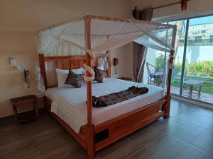 a bedroom with a canopy bed and a large window at DOGO E ILARIA Bed & Breakfast in Nungwi