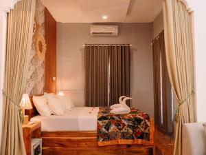 a bedroom with a bed with a swan on it at Brezze Garden Village in Mataram