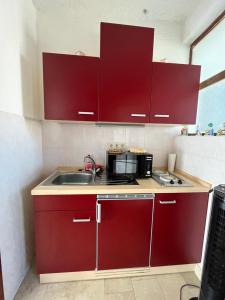 Una cocina con gabinetes rojos y un fregadero. en Apartment Antonia, en Selce
