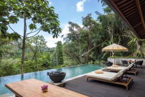 un patio extérieur avec une piscine, des chaises et une table dans l'établissement Impiana Private Villas Ubud, à Ubud